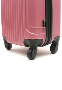 Pink hard-shell luggage with a textured surface, vertical ridges, black zipper and wheels, featuring a compact, rectangular design.
