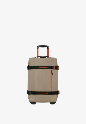 Valigia beige morbida con dettagli arancioni, manico telescopico, due cinghie nere, una tasca con zip frontale e ruote nere.