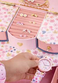 Rosa Schmuckkästchen mit floralen Design, das Ohrringe und eine pastellfarbene Uhr enthält. Verfügt über Ringhalter, einen Spiegel und einen goldenen Herzakzent.