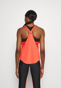 Canottiera sportiva rossa con design a dorso scoperto. Realizzata in tessuto leggero, presenta un orlo curvo e spalline nere a contrasto.