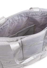 Bolsa de tela acolchada en color gris con herrajes en tono plateado, que presenta un bolsillo interior con cremallera y asas planas y duraderas.