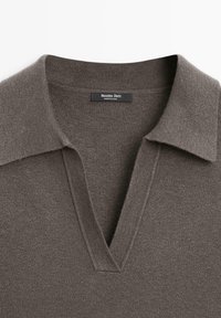 Maglione marrone con una consistenza morbida, dotato di scollatura a V e colletto piatto. L'etichetta riporta "Massimo Dutti". Tessuto liscio senza motivi visibili.