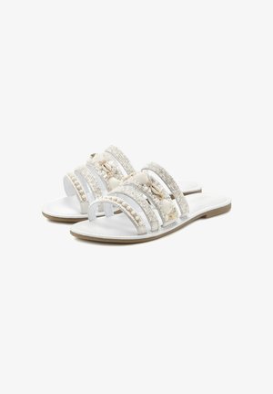 Weiße Sandalen mit drei breiten Riemen, verziert mit Muscheln und Perlen, ausgestattet mit einer flachen Sohle und einer glatten, lederähnlichen Textur.