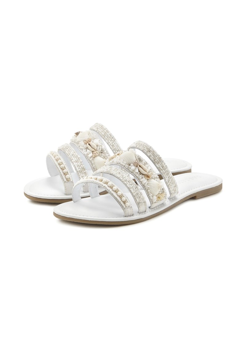 White sandals with three wide straps, adorned with shells and beads, featuring a flat sole and a smooth leather-like texture.