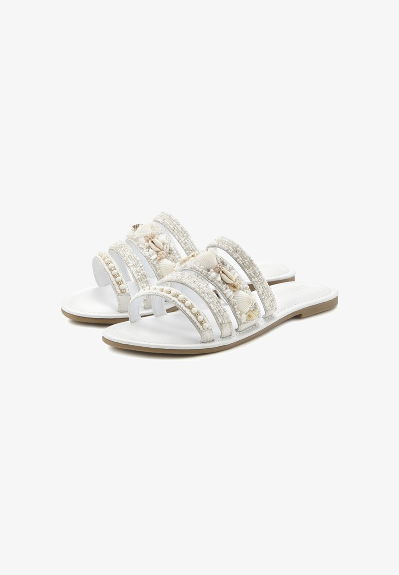 White sandals with three wide straps, adorned with shells and beads, featuring a flat sole and a smooth leather-like texture.