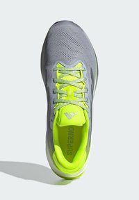 Chaussure de sport avec une tige en mesh gris, des accents jaune néon vifs et des lacets texturés. Comprend une semelle amortie et une semelle intérieure de marque.