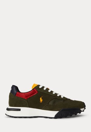 Baskets vert olive avec semelle blanche, accents rouges et jaunes, lacets blancs, semelle noire et logo jaune sur le côté.
