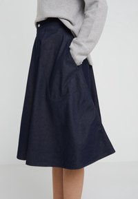 Donkerblauwe denim midi-rok met een uitlopende vorm, zijzakken en een hoge taille. Kenmerkt zichtbare stiksels en een knoopdetail aan de voorkant.