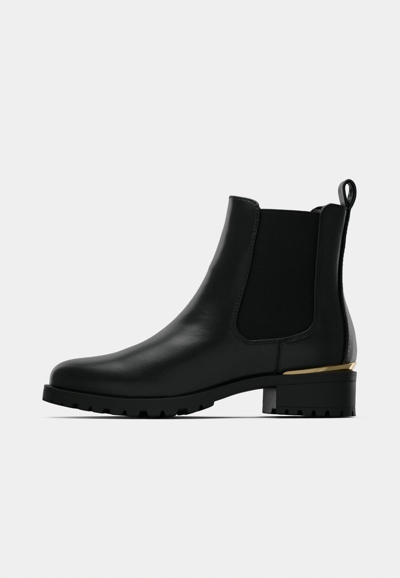 Botte Chelsea en cuir noir avec semelle épaisse, panneaux élastiques sur les côtés, boucle au talon et accent doré à l'arrière du talon.