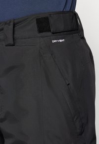 Juodos lauko kelnės, pagamintos iš lygaus sintetinio audinio, su reguliuojamu diržu, užsegamu Velcro, ir siuvinėtu „DRYVENT“ logotipu šone.