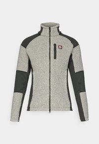Chaqueta de forro polar en gris claro con mangas en gris oscuro, cuello alto, cremallera completa y un pequeño bolsillo en el pecho con un logo. Detalle de tela texturizada.