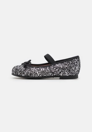 Ballet flats à paillettes noires avec un bout rond, semelle plate et un nœud décoratif à l'avant. Présente une sangle élastique pour un maintien sécurisé.