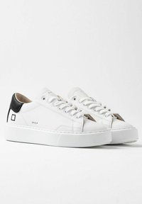 Hvide lædersneakers med en sort tekstureret hæl og platformssål. Har snørebåndsdesign og logo-detalje på siden.