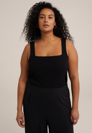 Black ribbed tank top with a square neckline and wide straps, paired with loose black trousers. Smooth texture and minimal detailing.
