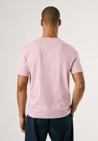 Světle růžové tričko s kulatým výstřihem a krátkými rukávy, vyrobené z měkké bavlny, s rovnou siluetou a minimálními švy.