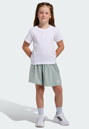 White short-sleeve t-shirt with a subtle three-stripe logo, paired with light green shorts featuring small texture details. White sneakers.