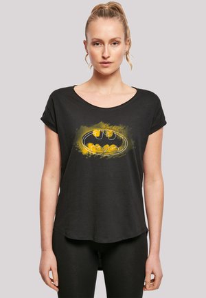 Svart t-skjorte med korte ermer og rund hals, med en Batman-logo i gul og hvit grafikk. Laget av myk, pustende stoff.