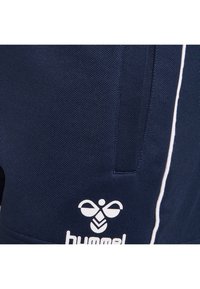 Tmavě modré sportovní šortky z texturované látky, s bílým pruhem po straně a bílým logem na lemu.