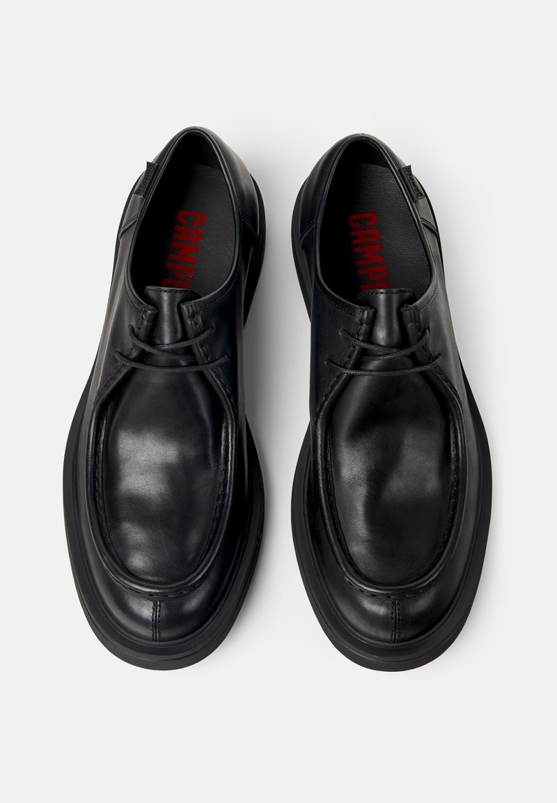 Pair of black leather lace-up shoes with rounded toes and thick soles, viewed from above on a white background.