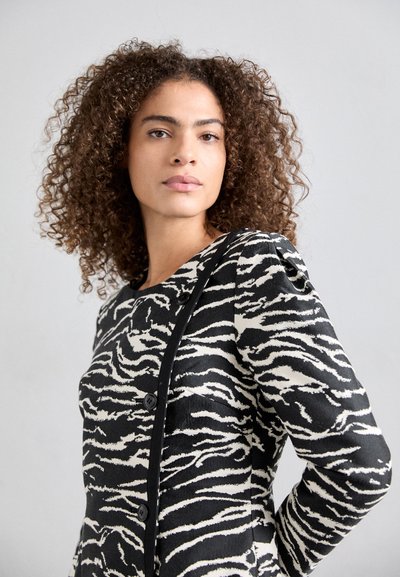 Black and white zebra-patterned coat with texture, featuring a round neckline, button accents, and contrasting trim.