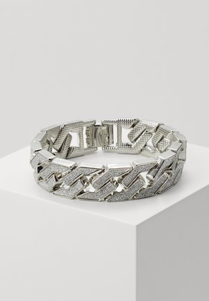 Sølv kjede armbånd med teksturerte og glatte ledd, som veksler mellom polerte og glitrende elementer, med en sikker lås.