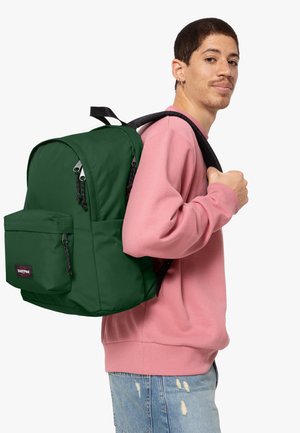 Mochila verde con bolsillos con cremallera, fabricada en tejido duradero. Correas ajustables, textura suave y un parche con el logo en la parte frontal.