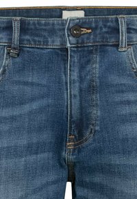 Blaue Denim-Jeans mit Five-Pocket-Design, Knopfverschluss und kontrastierenden goldenen Nähten. Der Stoff hat eine glatte, leicht strukturierte Oberfläche.