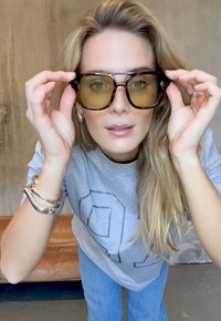 Kilpkonnakujulised päikeseprillid, millel on suured, ümarad läätsed ja õhuke must raam. Läätsed on kollaka tooniga, pakkudes raami suhtes selget kontrasti.