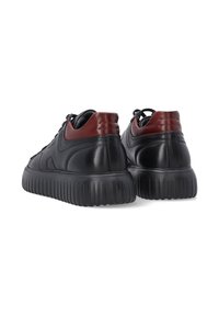 Zwarte leren sneakers met een roodaccent op de hiel, ronde neus en een geprofileerde rubberen zool met diepe groeven voor grip.