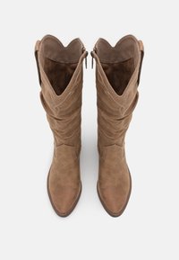 Brązowe zamszowe kozaki za kolano z marszczonym wzorem, spiczastym noskiem i falistymi górnymi krawędziami. Posiadają suwaki po wewnętrznych stronach.