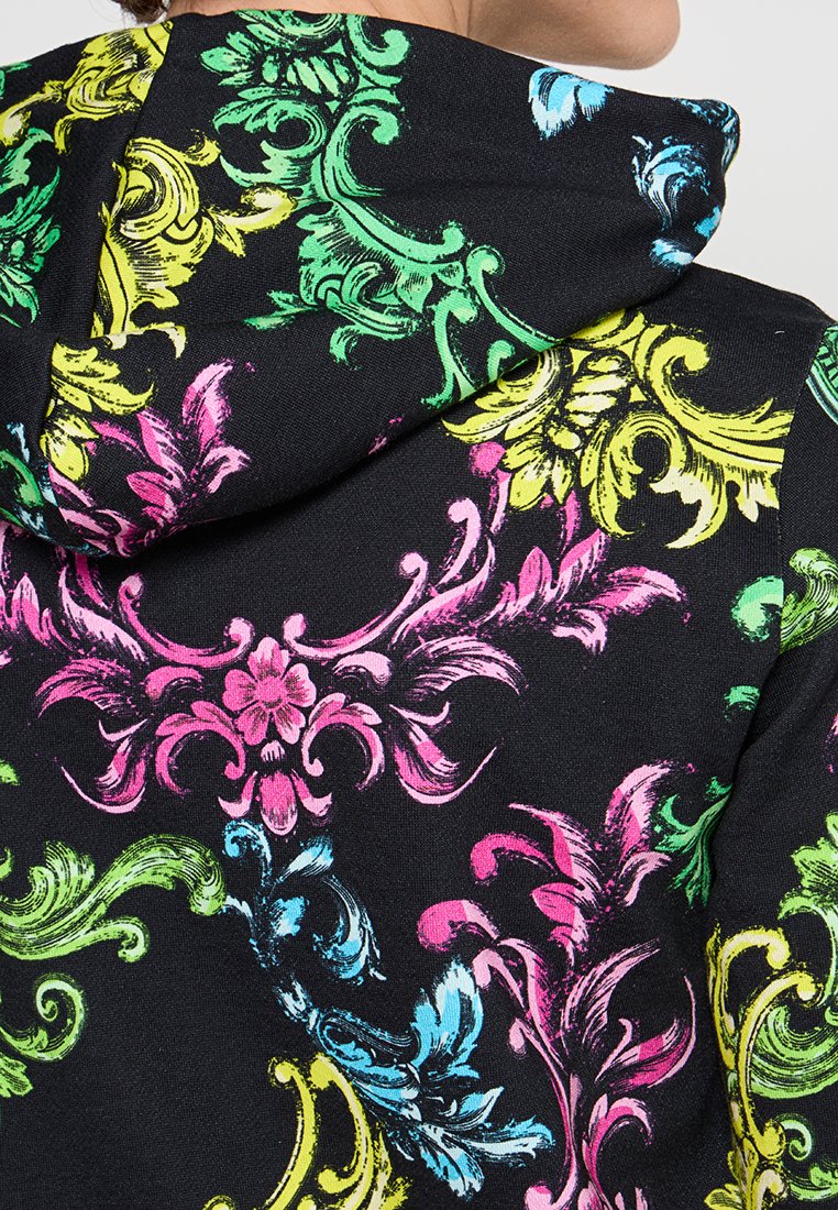 Bluza z kapturem z czarnym tłem i żywymi wzorami kwiatowymi w odcieniach różu, zieleni, żółci i niebieskiego, wykonana z teksturowanej tkaniny.