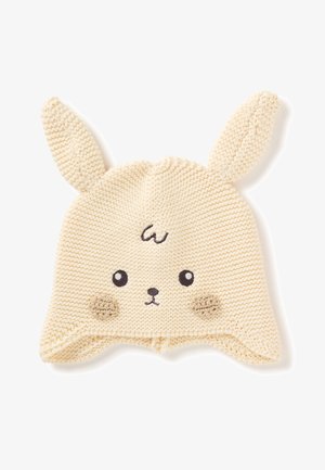 Cappellino per neonati color crema, lavorato a maglia, con orecchie da coniglio, occhi ricamati, naso, guance e una piccola spirale sulla fronte.