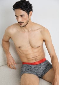 Puma márkájú, szürke, testhezálló boxer alsónadrág, fekete, ismétlődő mintával, piros elasztikus derékpánttal. Puha, rugalmas anyagból készült.