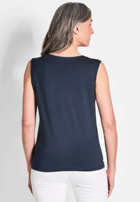 Marineblauw mouwloos shirt van zachte stof, met een ronde halslijn en een rechte zoom. Eenvoudig ontwerp zonder patronen of accenten.