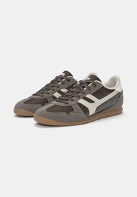 Sneakers a bassa profilo con parte superiore in suede e pelle grigia, dettagli bianchi e suola in gomma marrone. Chiusura con lacci e collo imbottito.
