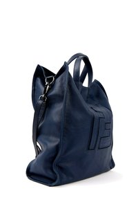 Grand sac à main en cuir bleu marine avec doubles anses et bandoulière détachable, présentant un motif géométrique embossé sur le côté.