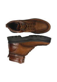 Botines de cuero marrón con acabado de ante, diseño con cordones, detalles texturizados y una suela de goma negra resistente.