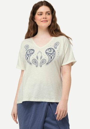 T-shirt à manches courtes crème clair avec un col en V, présentant un motif paisley bleu marine au centre. Texture douce, coupe décontractée.