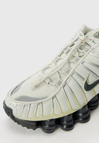 Ljusgrå sneakers med mesh-överkonstruktion, silverdetaljer, en unik sula-design och rundad tå. Har elastiska snören och en vadderad krage.