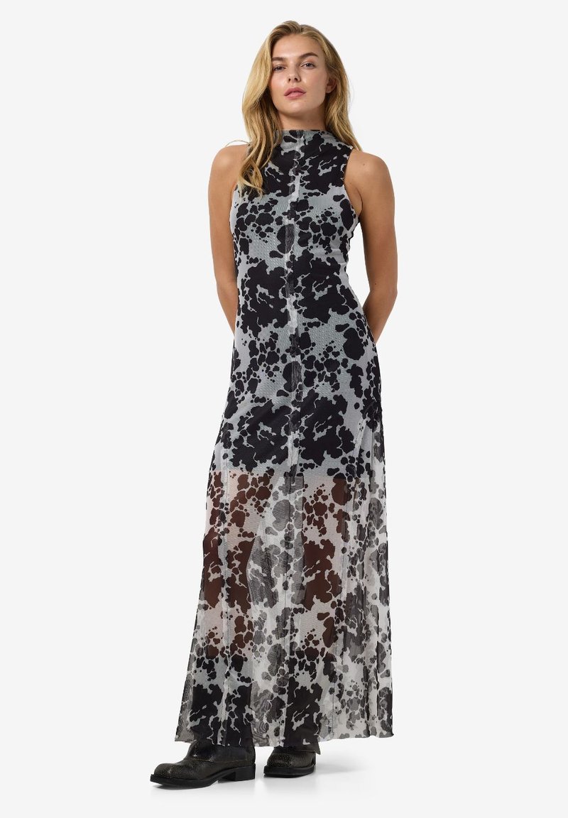 Rochie maxi dintr-o țesătură ușoară și transparentă, cu un model de tip vacă în culorile negru și gri. Decolteu înalt și o siluetă dreaptă.