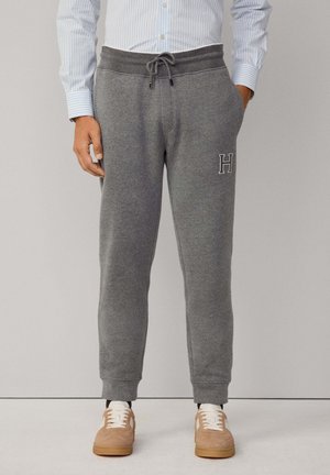 Grå bomullsbyxor i sweatpants-stil med elastisk midja, dragsko och ribbade avslutningar. Har en liten broderad "H" på vänster lår.