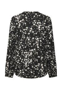 Blouse noire avec un motif floral blanc, manches longues, col rond et légère courbe à l'ourlet. Tissu doux et léger.