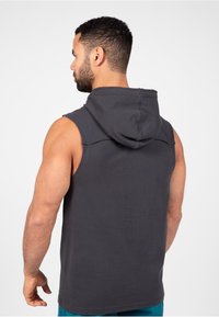 Donkergrijze mouwloze hoodie van katoen. Heeft een eenvoudig ontwerp met een ronde zoom en een relaxte pasvorm.