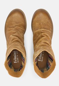 Par de botines tobilleros de ante marrón claro desgastados con diseño arrugado y forro de tela a rayas, vistos desde arriba.