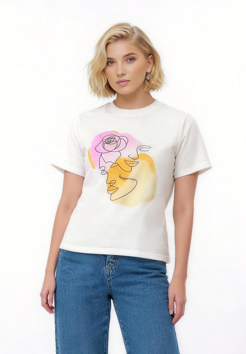 Νεαρή γυναίκα με κοντά ξανθά μαλλιά φοράει λευκό T-shirt με αφηρημένο σχέδιο προσώπου και τριαντάφυλλου σε ροζ, κίτρινο και πορτοκαλί, συνδυασμένο με μπλε τζιν.