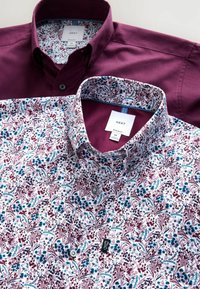 Dvoje košieľ: jedny hladké burgundské, druhé biele s kvetinovým vzorom v burgundskej, modrej a zelenej farbe. Obidve majú gombíkové zapínanie a golier.