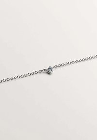 Pulsera de cadena plateada con una piedra preciosa redonda de color azul claro en un engaste tipo bisel, destacando un diseño elegante y minimalista.