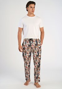 Witte katoenen T-shirt gecombineerd met gestreepte pyjamabroek met cartoonfiguren in levendige kleuren op een donkere achtergrond.