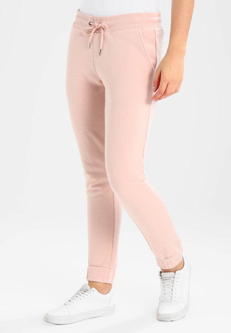 Ljusrosa sweatpants i mjukt material, med dragsko i midjan, sidofickor och åtsittande mudd. I kombination med vita sneakers.