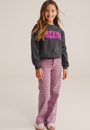 Sweat-shirt gris avec l'inscription rose "Cherish", associé à un pantalon à motifs léopard rose et des chaussures roses. Le mannequin a de longs cheveux ondulés.
